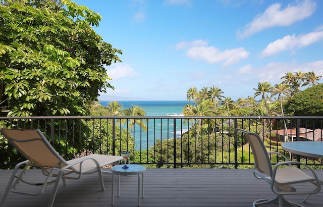 wooden terrace featuring a water view and a beach view