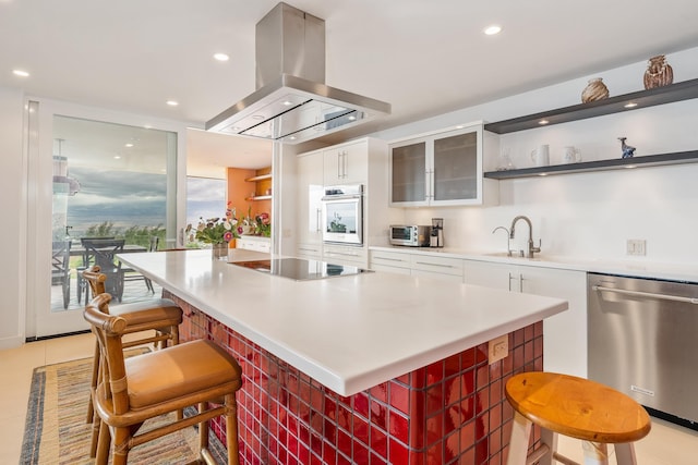 kitchen featuring island exhaust hood, a kitchen breakfast bar, dishwasher, white cabinets, and oven