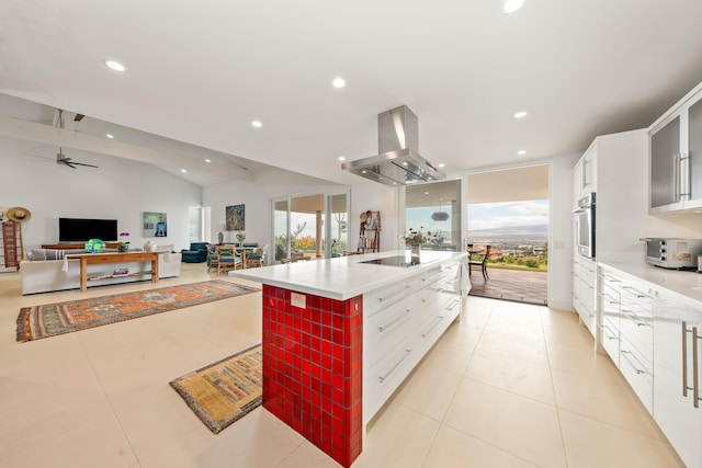 kitchen featuring ceiling fan, stainless steel oven, island exhaust hood, an island with sink, and vaulted ceiling