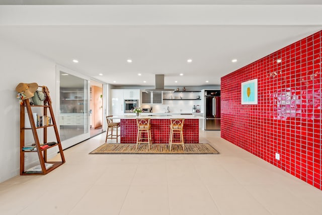 kitchen featuring sink, stainless steel appliances, a kitchen breakfast bar, island range hood, and white cabinets