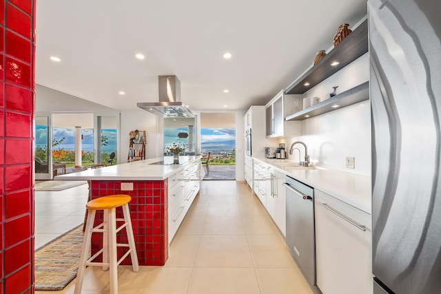 kitchen featuring white cabinetry, stainless steel appliances, island exhaust hood, a breakfast bar area, and a kitchen island