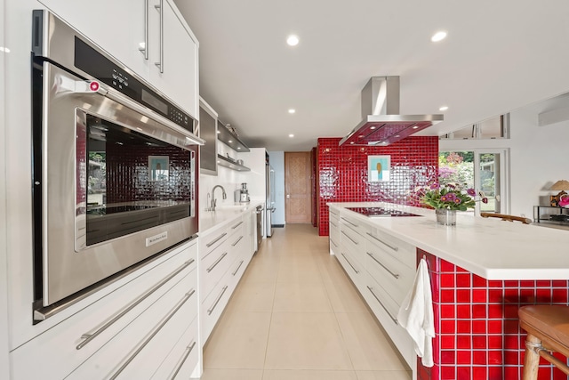 kitchen with white cabinets, stainless steel oven, black electric stovetop, and island exhaust hood