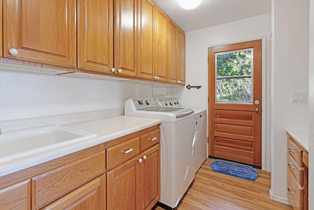 laundry room featuring cabinets, light wood-type flooring, and washing machine and dryer