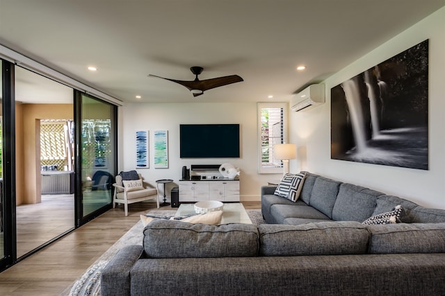 living room featuring an AC wall unit, ceiling fan, and light wood-type flooring