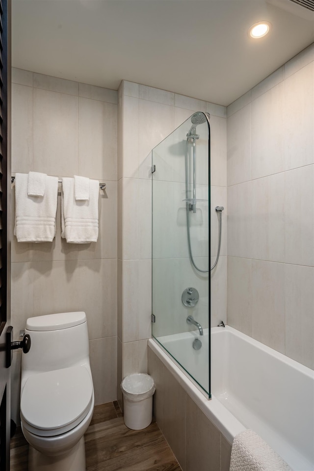 bathroom with hardwood / wood-style floors, toilet, and combined bath / shower with glass door