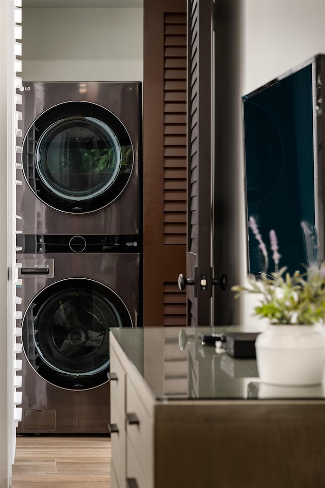 laundry room featuring stacked washer and clothes dryer and light wood-type flooring