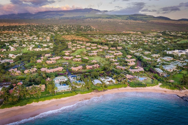 aerial view at dusk featuring a view of the beach and a water and mountain view