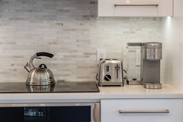 details featuring white cabinets, decorative backsplash, black cooktop, and oven