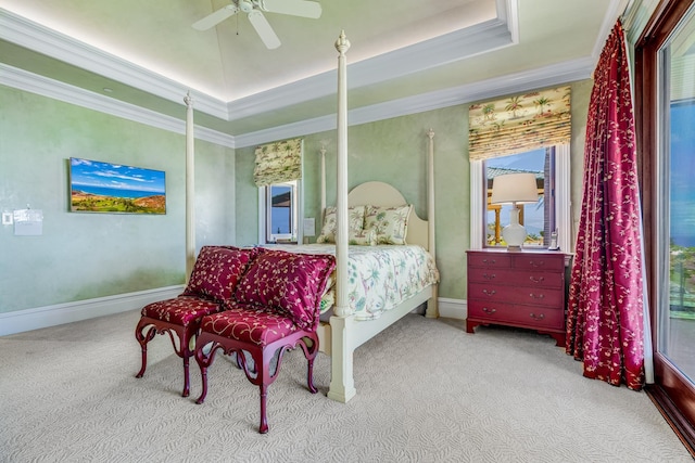 carpeted bedroom with a raised ceiling, ceiling fan, and crown molding