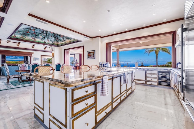 kitchen featuring sink, a kitchen island, light stone counters, crown molding, and white cabinets