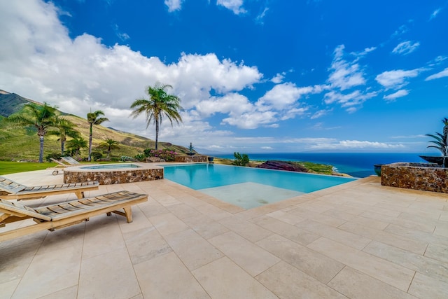 view of swimming pool with an in ground hot tub, a patio area, and a water and mountain view