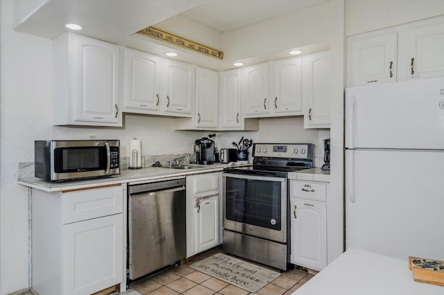 kitchen featuring light tile patterned floors, light countertops, appliances with stainless steel finishes, white cabinets, and a sink