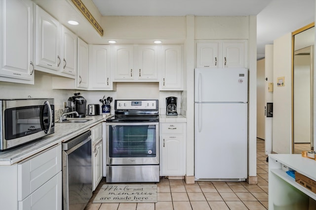 kitchen with appliances with stainless steel finishes, light countertops, white cabinets, and a sink