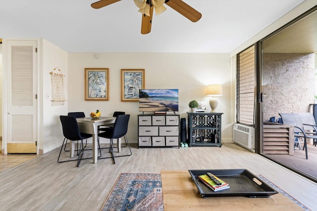 living area with a wall mounted AC, baseboards, and wood finished floors