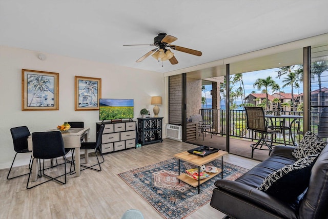 living room featuring a ceiling fan, a wall of windows, and wood finished floors