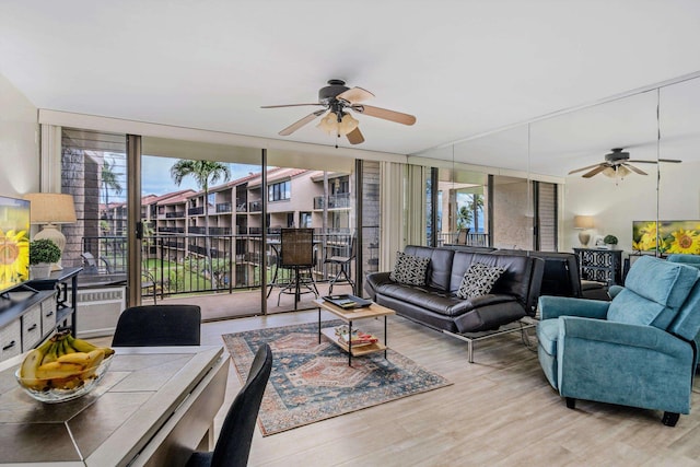 living area with ceiling fan, a wall of windows, and wood finished floors