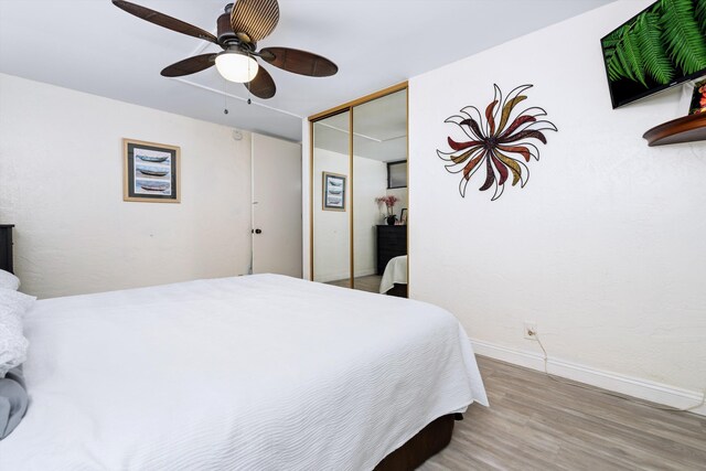 bedroom with a ceiling fan, a closet, baseboards, and wood finished floors