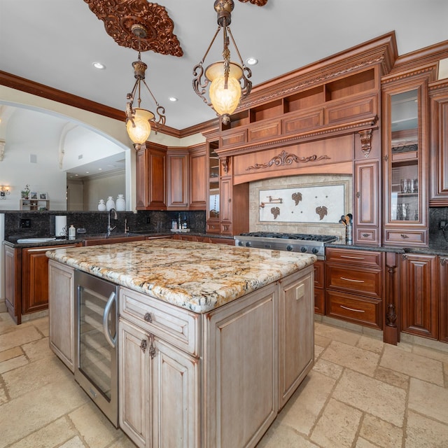 kitchen with wine cooler, hanging light fixtures, tasteful backsplash, a kitchen island, and light stone countertops