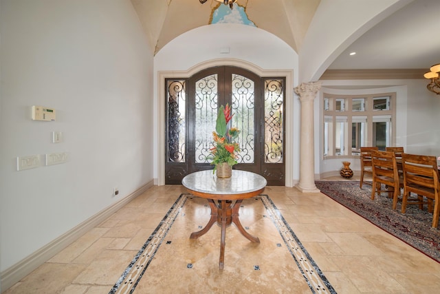 entrance foyer featuring french doors, ornamental molding, lofted ceiling, and ornate columns