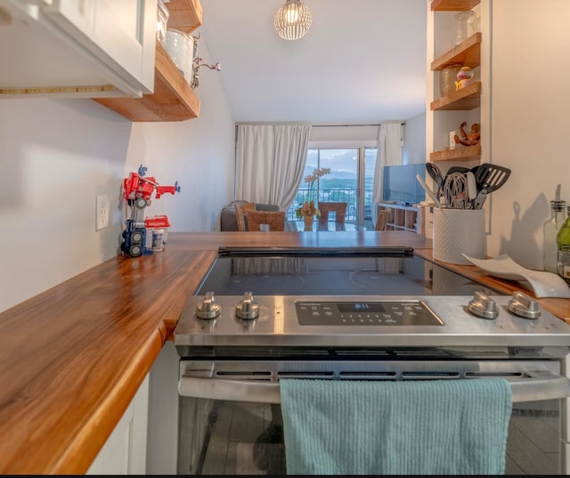 kitchen featuring white cabinets, wood-type flooring, wood counters, and stainless steel range with electric cooktop