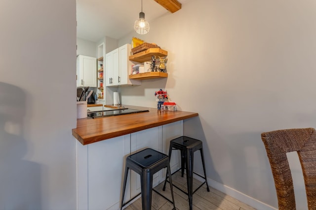 bar with white cabinets, pendant lighting, light wood-type flooring, and butcher block counters