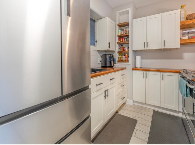 kitchen featuring backsplash, wooden counters, appliances with stainless steel finishes, light hardwood / wood-style floors, and white cabinetry