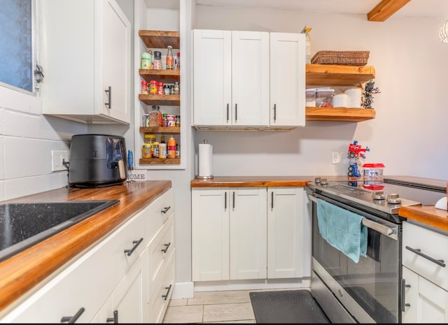 kitchen featuring butcher block countertops, white cabinetry, and stainless steel range with electric cooktop