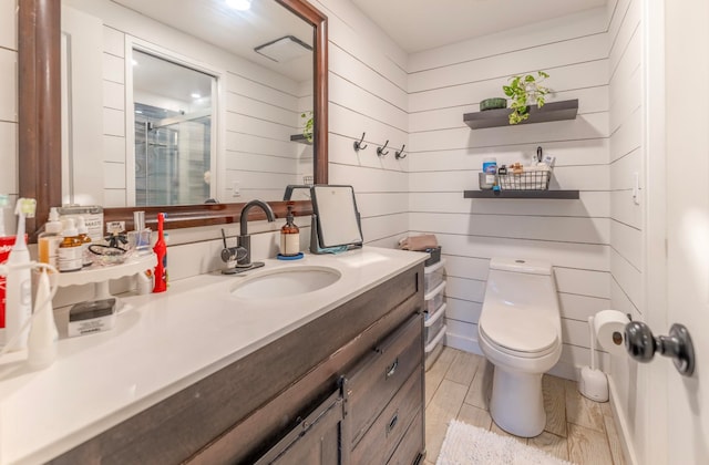 bathroom with vanity, toilet, a shower with shower door, and wood walls