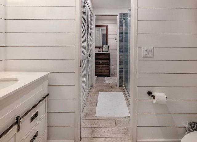 bathroom featuring wood walls, vanity, wood-type flooring, and an enclosed shower