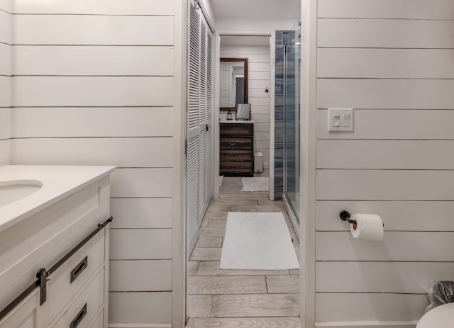 1063 Lower Main St Unit 315, Wailuku, HI 96793 - bathroom featuring vanity, a stall shower, wood finished floors, wooden walls, and a closet