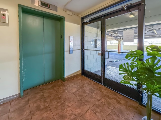 entryway with tile patterned floors, elevator, and french doors