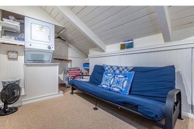 living room with stacked washing maching and dryer, lofted ceiling with beams, wood walls, and carpet floors