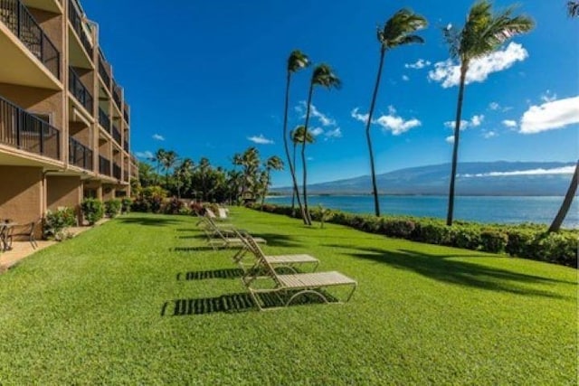 surrounding community with a water and mountain view and a lawn