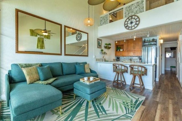 living room with ceiling fan, a towering ceiling, dark hardwood / wood-style floors, and rail lighting