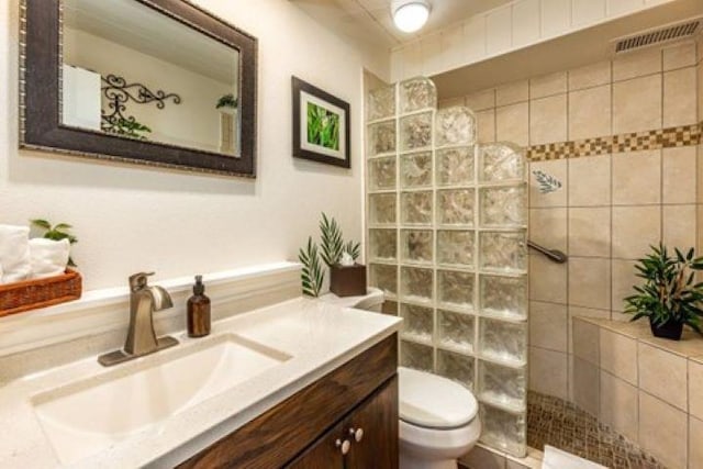 bathroom featuring vanity, toilet, and tiled shower