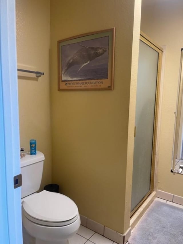 bathroom featuring toilet, a shower with door, and tile patterned flooring