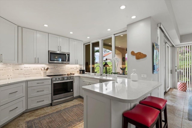 3150 Wailea Alanui Dr Unit 3007, Kihei, HI 96753 - kitchen with stainless steel appliances, tasteful backsplash, a peninsula, a kitchen breakfast bar, and recessed lighting