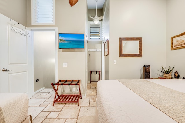 tiled bedroom with ceiling fan and a high ceiling