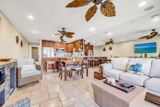 tiled living room featuring ceiling fan and a stone fireplace