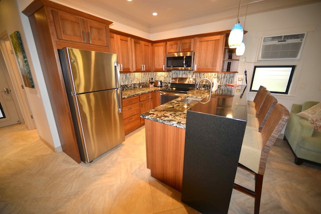 kitchen with brown cabinets, dark stone counters, stainless steel appliances, a peninsula, and backsplash