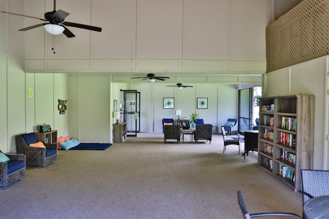 miscellaneous room featuring carpet flooring, a towering ceiling, a decorative wall, and ceiling fan