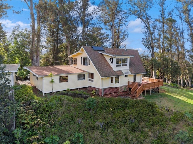 rear view of house featuring a yard, a deck, and solar panels