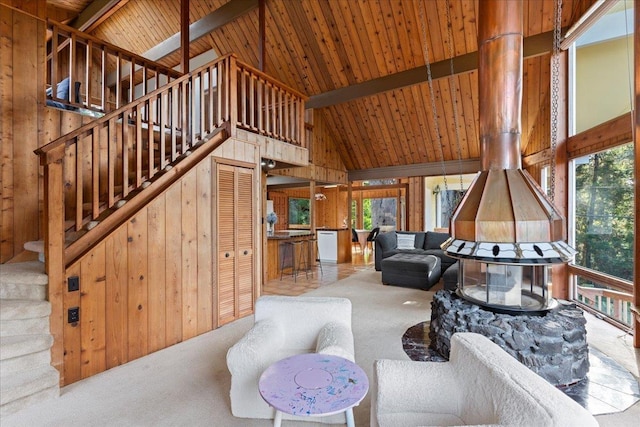 living room featuring carpet floors, a wood stove, beamed ceiling, and wood walls