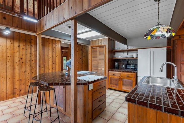 kitchen featuring beamed ceiling, tile countertops, sink, and wood walls