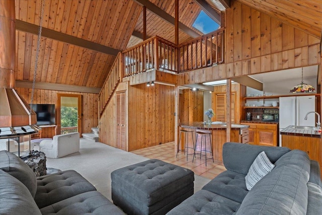 living room with wood ceiling, sink, lofted ceiling with beams, and wood walls