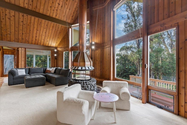 carpeted living room with wood ceiling, wooden walls, high vaulted ceiling, and a wealth of natural light