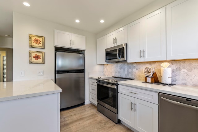 kitchen with white cabinets, decorative backsplash, light hardwood / wood-style floors, light stone counters, and stainless steel appliances