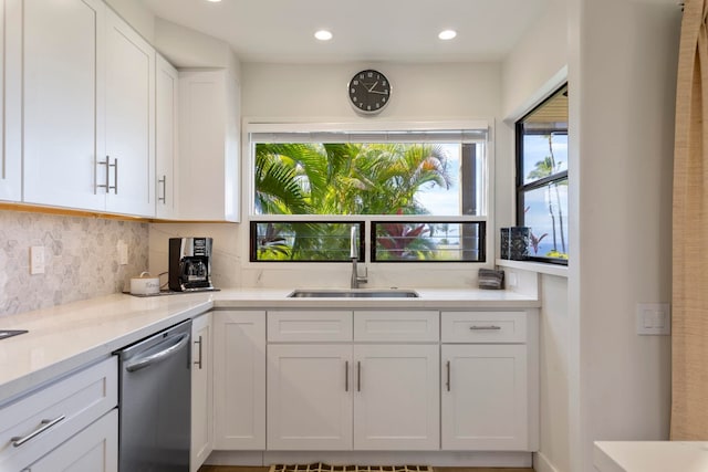 kitchen featuring stainless steel dishwasher, white cabinets, sink, and tasteful backsplash