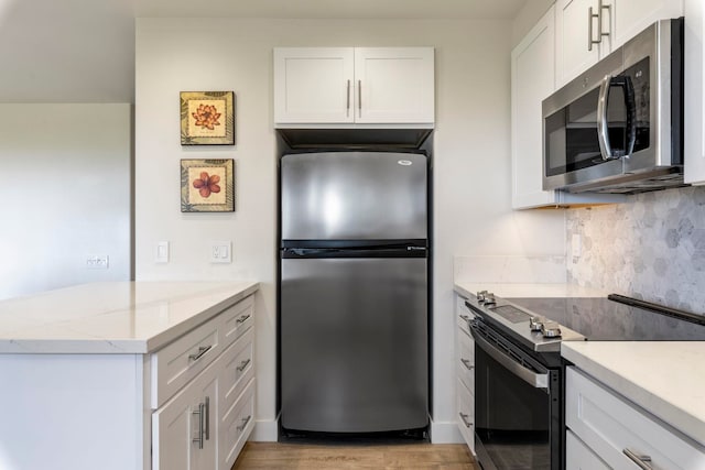 kitchen featuring white cabinets, light stone countertops, tasteful backsplash, light hardwood / wood-style floors, and stainless steel appliances