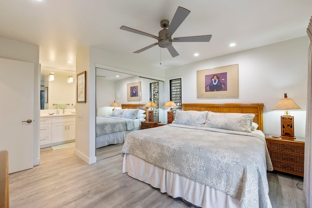 bedroom featuring ceiling fan, light hardwood / wood-style floors, and ensuite bath